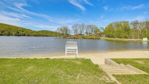 A lakeside view with a white bench and wooden steps leading to the water.