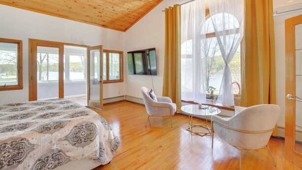 A spacious bedroom with a large bed, two chairs, a small table, and a TV.
