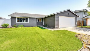 A modern two-story house with a garage, a well-maintained lawn, and a small garden area. - Updated Family Home w/ Fenced Yard in Yakima! (Yakima)