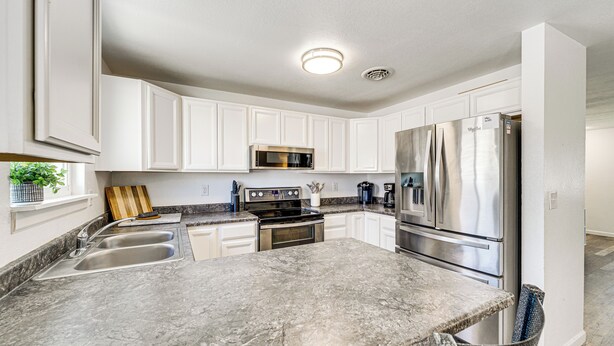 A modern kitchen with white cabinets, stainless steel appliances, and a granite countertop. - Updated Family Home w/ Fenced Yard in Yakima! (Yakima)