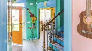 Una escalera con barandilla de madera y una guitarra apoyada en la pared.
