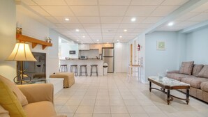 A spacious living area with a sofa, a coffee table, and a kitchen in the background. - Patio + Pond View: Serene Cape Cod Escape (Mashpee)