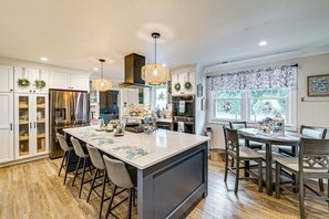 A modern kitchen with a large island, bar stools, and a dining area with a chandelier. - 2 Mi to Beach: Bbq-ready Home in North Cape May! (Cape May)
