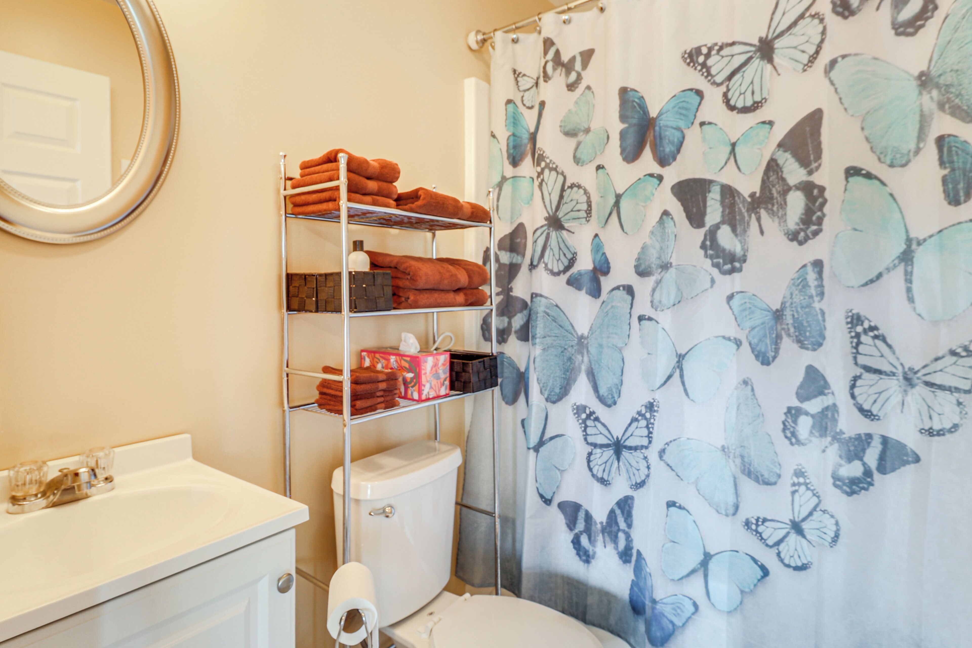 Une salle de bain équipée de toilettes, d’un lavabo et d’étagères où sont rangées les serviettes.