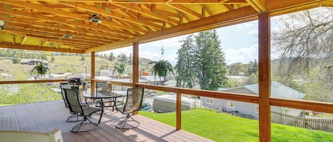 Eine Holzterrasse mit überdachtem Bereich, Gartenmöbeln und Blick auf ein Wohngebiet.