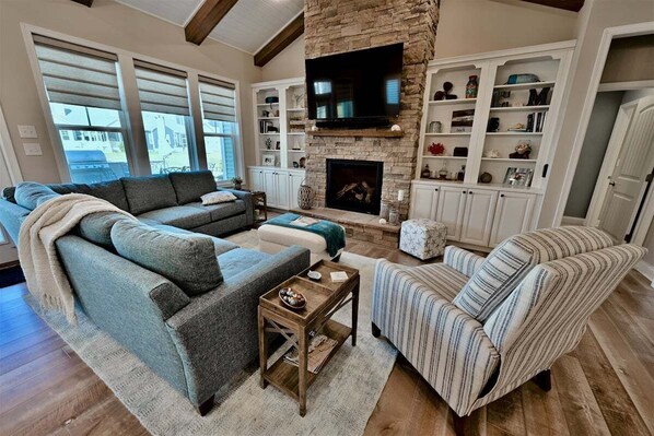A living room with a fireplace, a television, and built-in shelving.