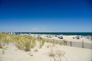 A beach with a wooden fence, sandy dunes, and umbrellas. - Rehoboth Beach, Dog Friendly, 5BR, 3 Full Baths, Arbor-Lyn Community, Sleeps 12 (Rehoboth Beach)