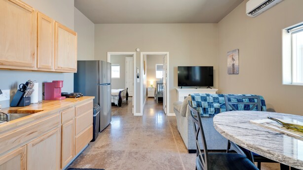 A modern kitchen with wooden cabinets, a refrigerator, a coffee maker, and a dining area with a marble table. - Walk to Wineries: Elgin Wine Country Retreat! (Elgin)
