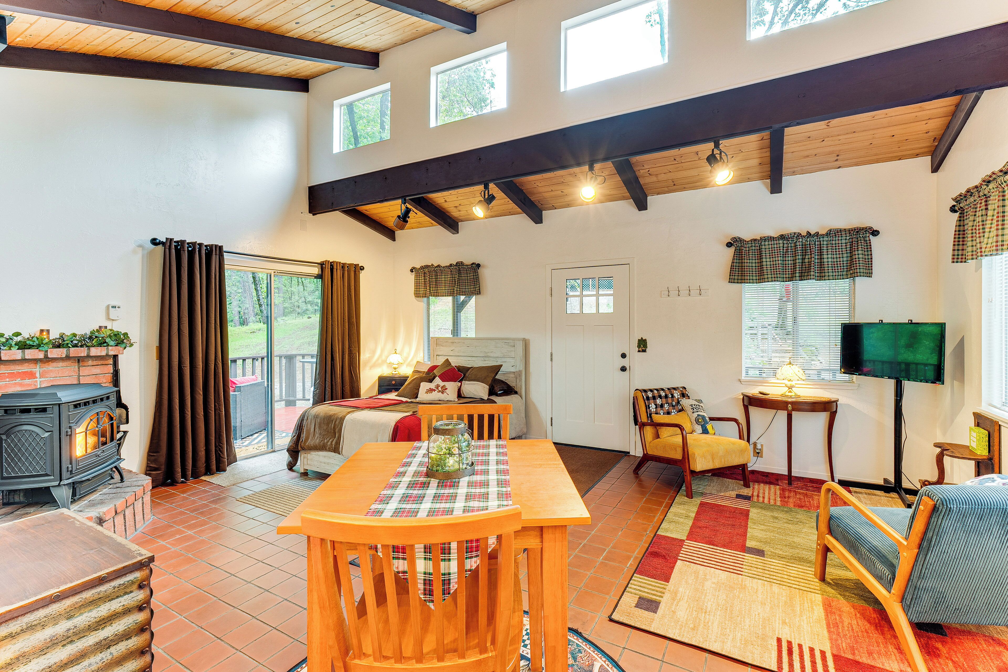 A cozy living room with a fireplace, a bed, a TV, and a dining area.
