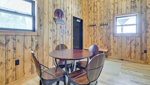 A wooden interior with a round table and chairs, a door, and a sign on the wall.