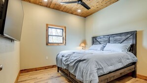 A bedroom with a wooden bed frame, a ceiling fan, a window, and a lamp.