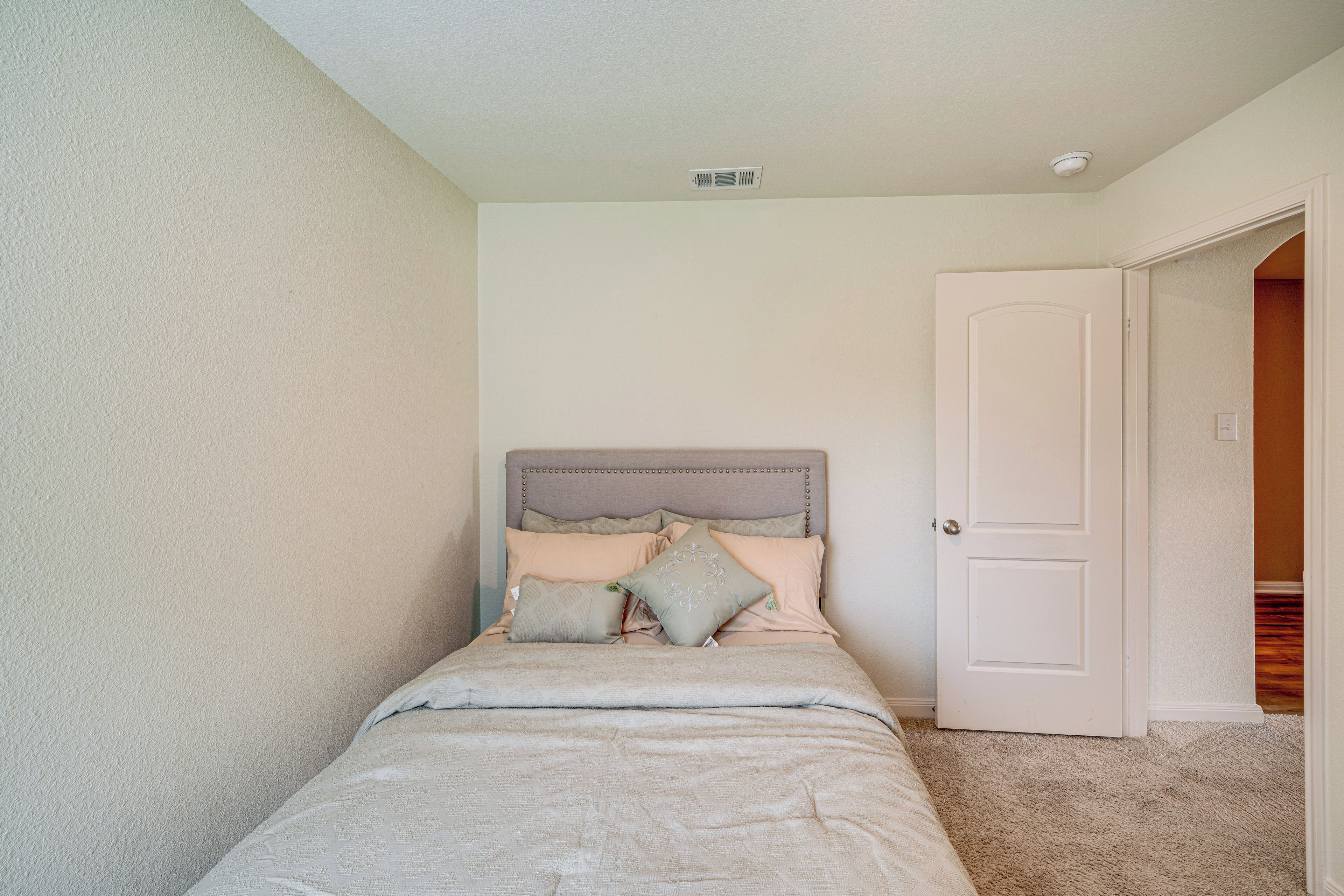 Una camera da letto con un letto, una porta e una griglia di ventilazione al soffitto.
