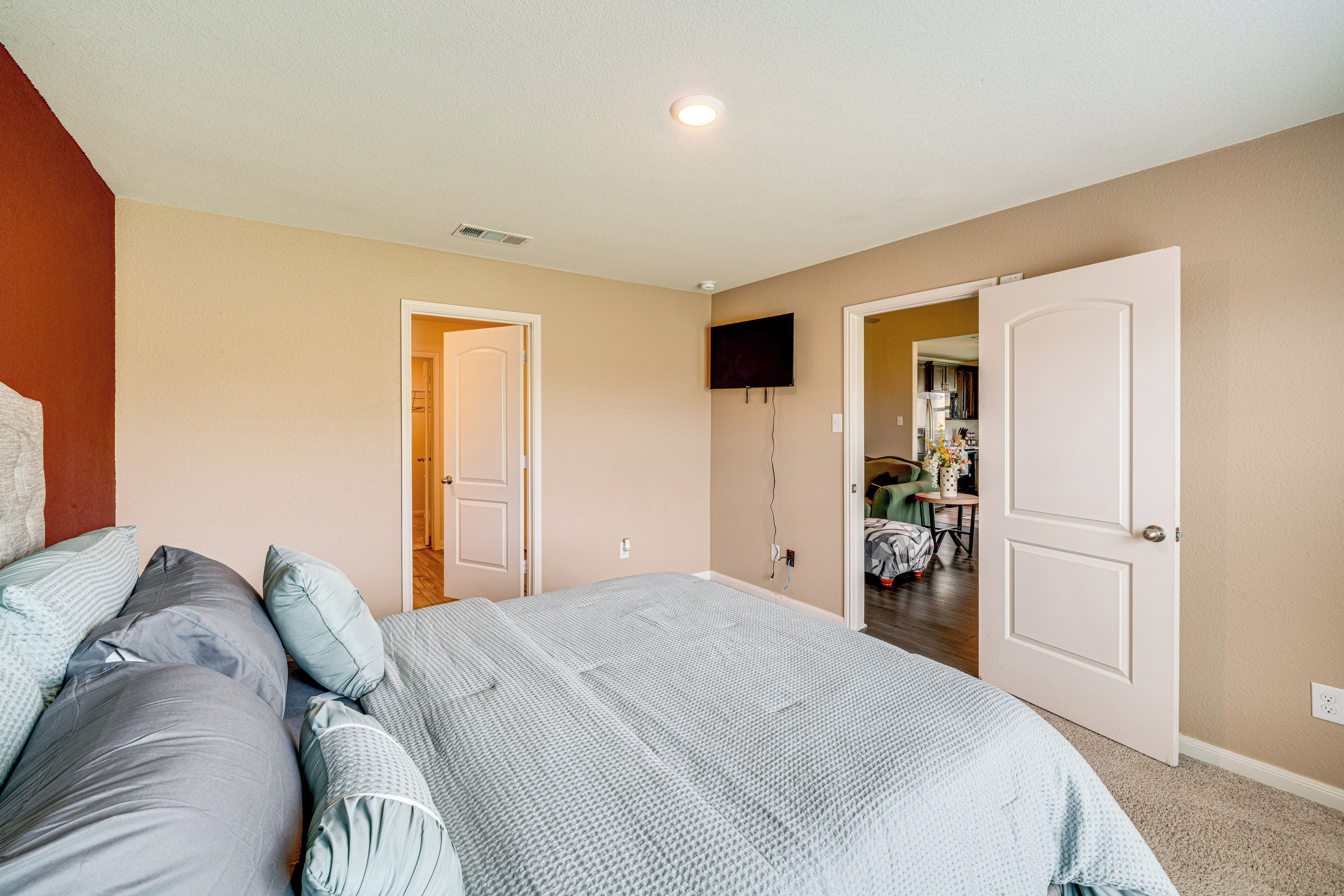 A bedroom with a bed, a television, and two doors leading to other rooms.