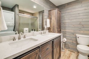 A bathroom with a double sink, a mirror, a toilet, and wooden paneling on the walls. - Game Room + Fireplace! Family Retreat in Pinetop (Pinetop)