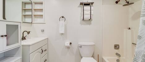 Un baño con inodoro, lavabo, espejo y ducha.