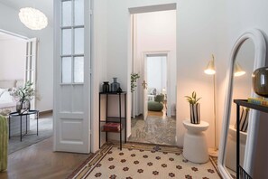 A modern interior with a patterned floor, a white door, a mirror, and a hallway leading to another room.