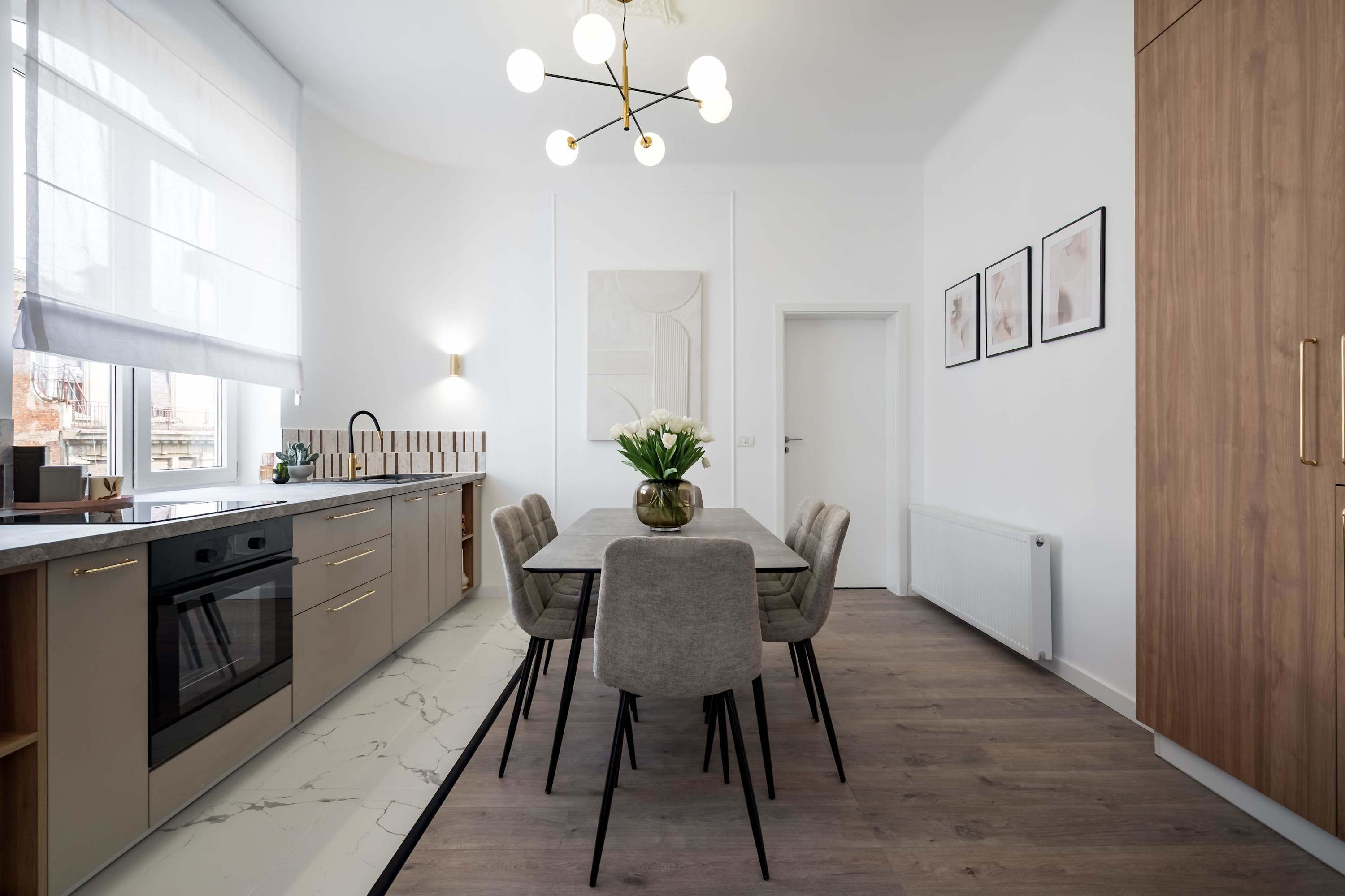 Een moderne keuken met een eetgedeelte, voorzien van een centraal kookeiland, hangende lampen en uitzicht op de stad.