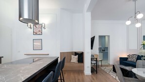Una cocina moderna con encimera de mármol, horno empotrado y una zona de estar con sofá y sillas.