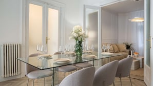 A modern dining area with a glass table, white chairs, and a vase of flowers. - Elegant 3BR Retreat - Steps Away Cismigiu Gardens (Bucharest)