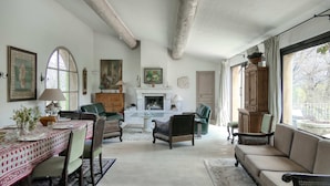 Un salon spacieux doté d’une cheminée, d’un coin repas et de grandes fenêtres.