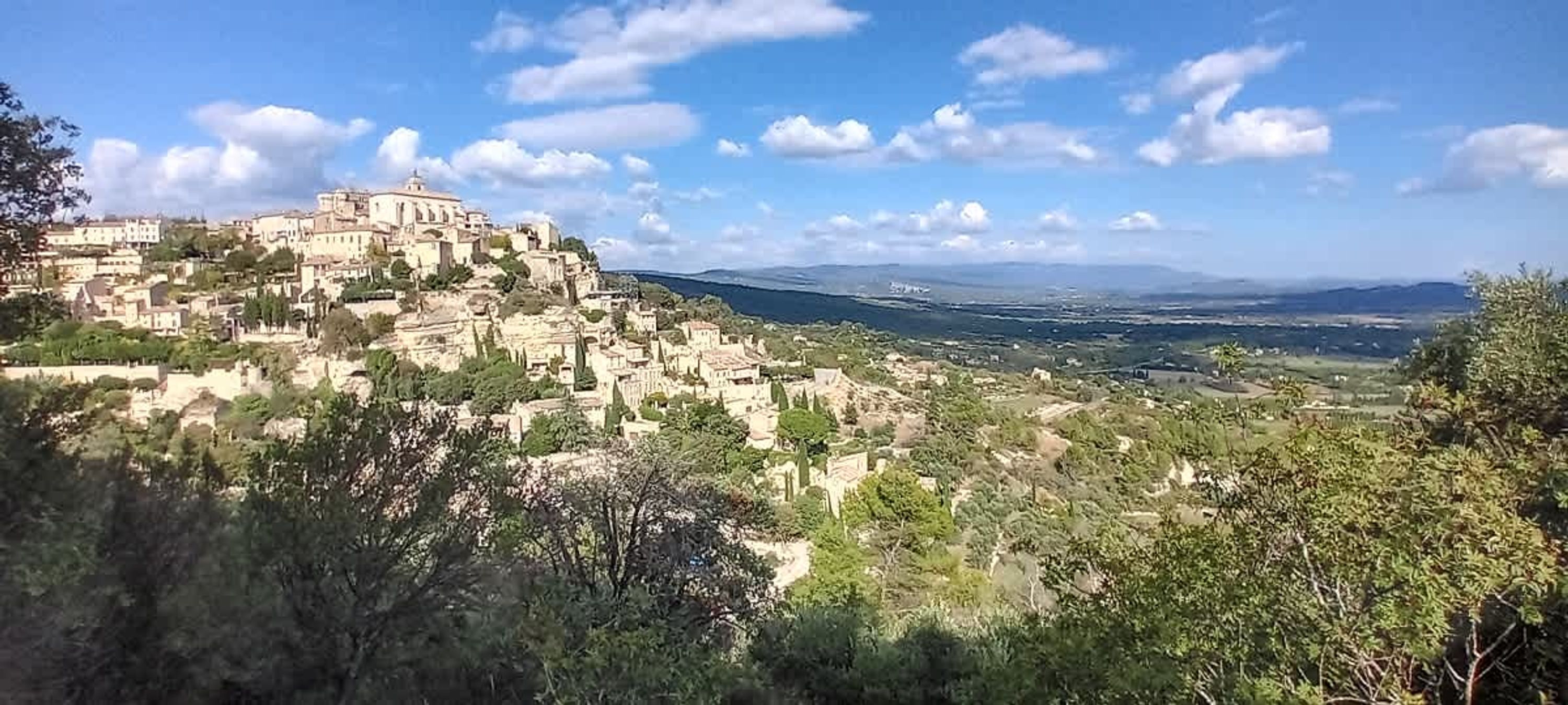 A hillside town with historic buildings, dense vegetation, and a clear sky.