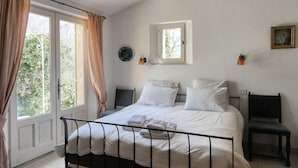 Une chambre à coucher avec un lit, une fenêtre, une chaise et une petite table.