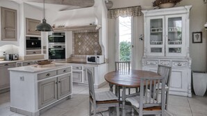 Une cuisine dotée d’un îlot central, de meubles blancs et d’une table à manger avec des chaises.