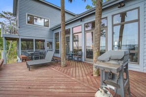A wooden deck with outdoor seating and a barbecue grill.