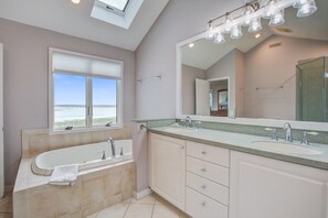 A modern bathroom with a large bathtub, two sinks, and a large mirror.