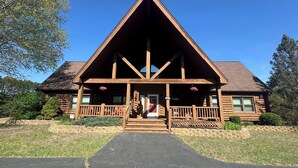 A log cabin with a triangular roof, wooden porch, and a front door. - Towering Pines Lodge: A Hidden Haven 10 Miles from Wisconsin Dells (Wisconsin Dells)