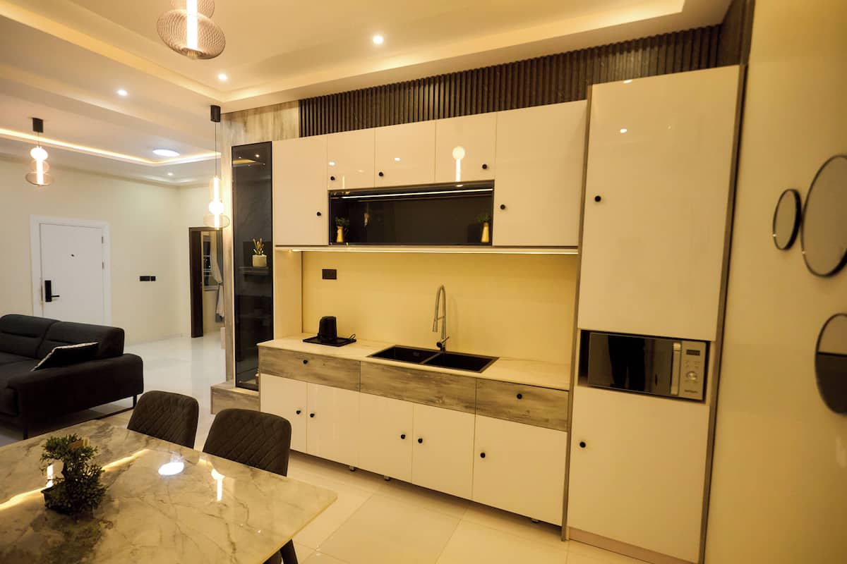 A modern kitchen with white cabinetry, a built-in microwave, and a sink.