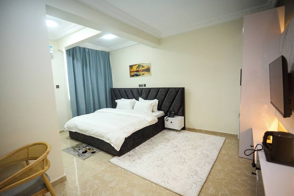 A bedroom with a bed, bedside table, and a wall-mounted TV.