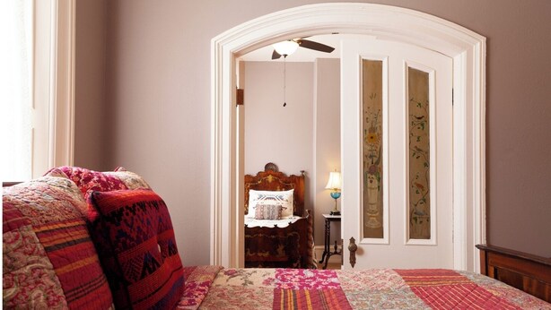 A bedroom with a large bed, a wooden headboard, a nightstand, and a lamp. - Bat Masterson - Historic Hotel Room (Cimarron)