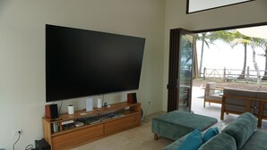 Una sala de estar moderna con un televisor de pantalla plana grande, un mueble de entretenimiento de madera y un sofá verde.