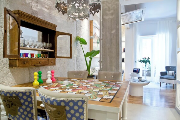 Un coin repas avec un jeu de société, des chaises, une table et un miroir au-dessus des étagères.