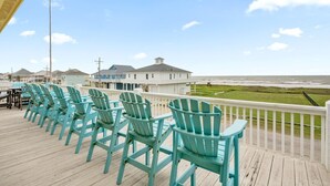 Eine Terrasse mit türkisfarbenen Adirondack-Stühlen mit Blick auf den Strand.
