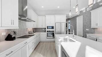 A modern kitchen with white cabinetry, stainless steel appliances, and a central island with a sink.