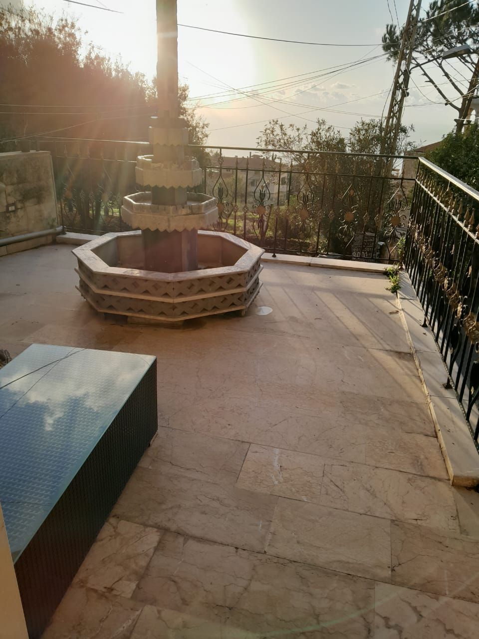 Un patio con una fuente central, una zona de estar y una barandilla de metal.