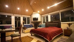 A bedroom with a large bed, a desk, and a chair. There are multiple windows and a television on a stand. - Chill Inn by Hansa  (Chemlane)