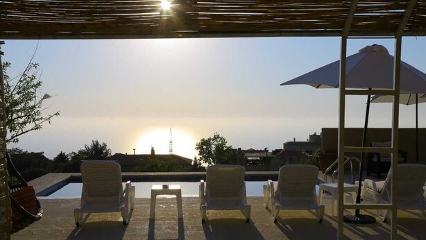 A sunlit outdoor seating area with a pool, lounge chairs, and umbrellas. - Chill Inn by Hansa  (Chemlane)
