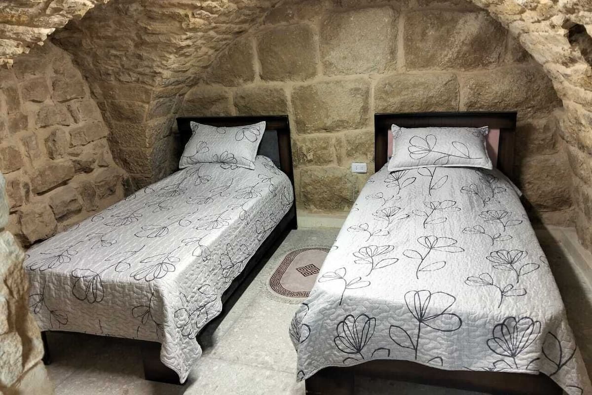 Two beds in a stone-walled alcove with patterned bedding.