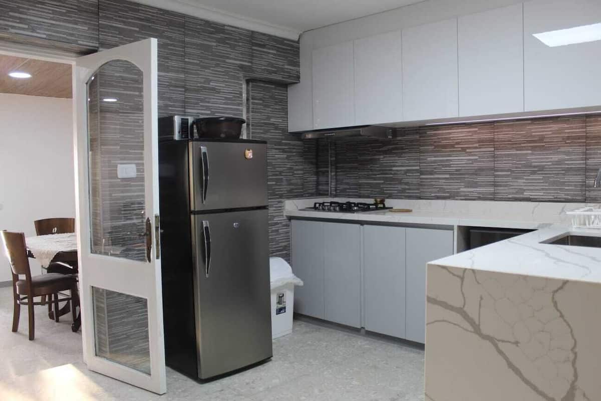 A modern kitchen with a refrigerator, stove, and white cabinets.