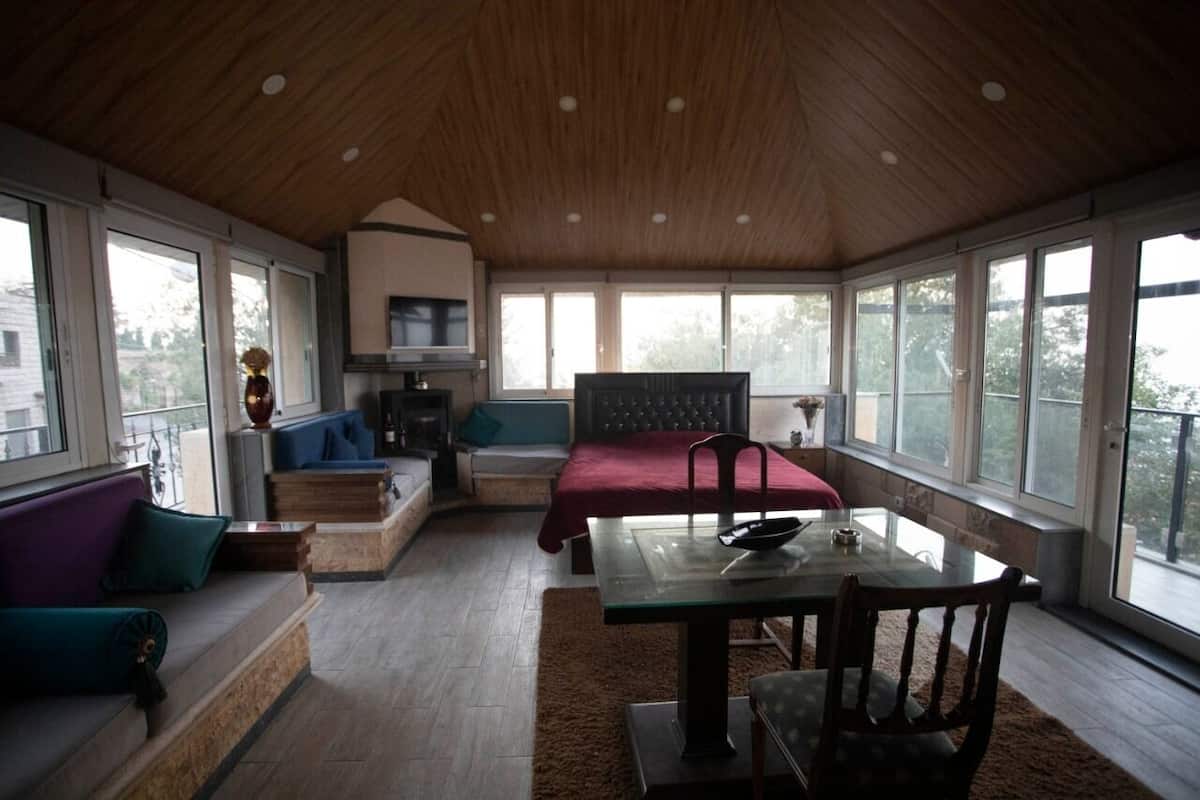 A spacious room with a high ceiling, a dining area, a sofa, and a television.