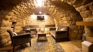 A cozy stone-walled room with a flat-screen TV, comfortable seating, and a patterned rug. - Chill Inn by Hansa  (Chemlane)