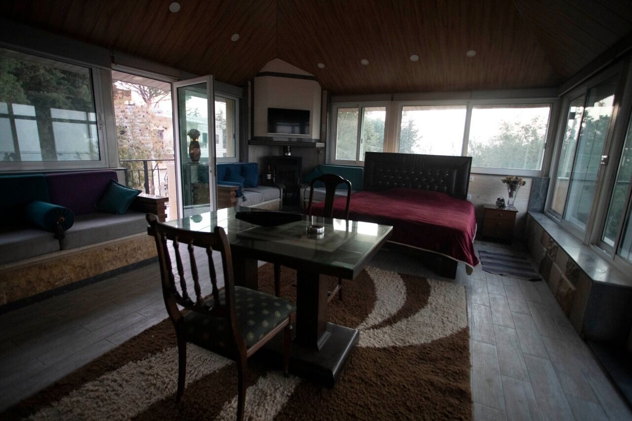 Una habitación amplia con un gran ventanal, una cama, una mesa de comedor con sillas y un sofá.