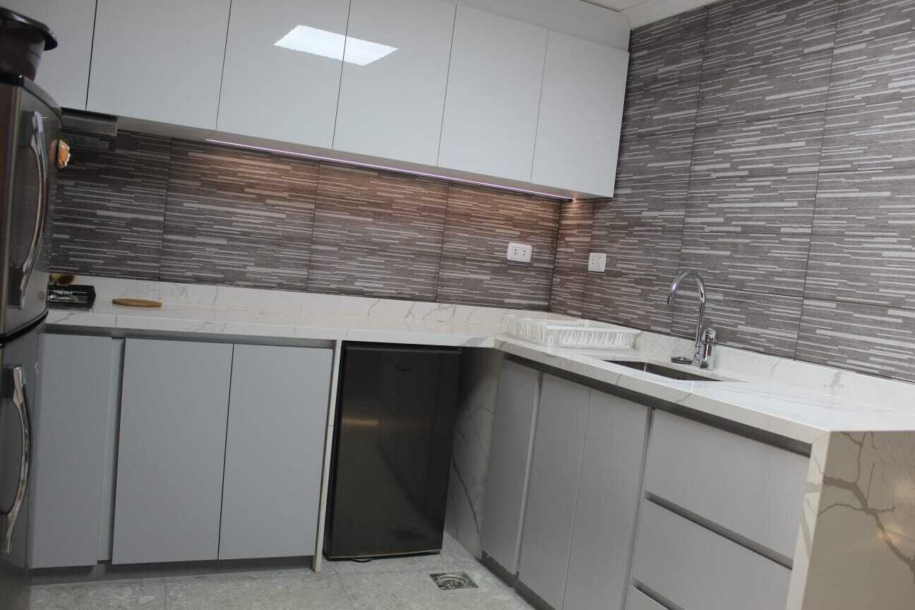 A modern kitchen with grey cabinets, a built-in dishwasher, and a marble countertop.