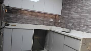 A modern kitchen with grey cabinets, a built-in dishwasher, and a marble countertop.