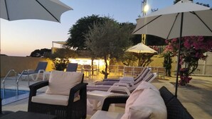 A poolside area with lounge chairs and umbrellas, a pool, and a building in the background. - Chill Inn by Hansa  (Chemlane)