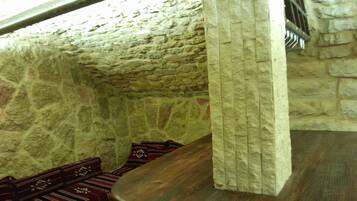 A stone-walled room with a wooden bench and a patterned rug.