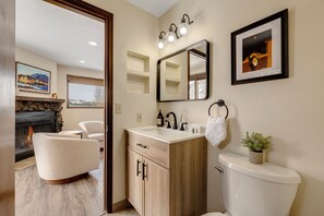 A bathroom with a wooden vanity, a white toilet, a mirror, and a framed picture on the wall. - Downtown Modern Frisco Getaway (Frisco)